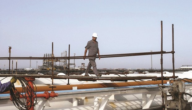 An Iranian worker walks on pipelines at an oil facility in the Khark Island, on the shore of the Gulf. Opec reported last week that Iran raised its monthly output by the most since international sanctions were lifted in January.