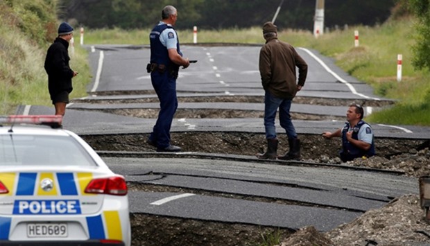 Policemen and locals look at damage following an earthquake, along a Highway
