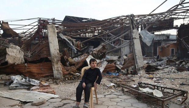 A boy sits amid the damage at a site hit by airstrikes