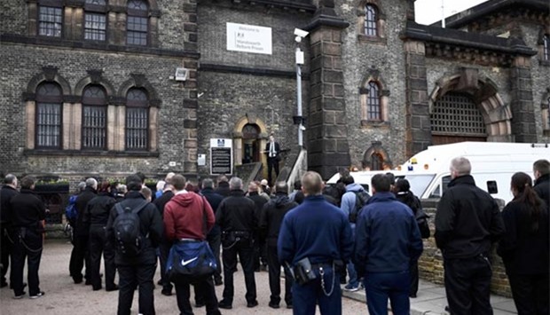 A man speaks to prison guards as they stand outside Wandsworth Reform Prison during an unofficial strike to protest against staffing levels and health and safety issues, in London on Tuesday.