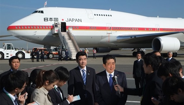 Japan's Prime Minister Shinzo Abe (C) speaks to reporters prior to boarding