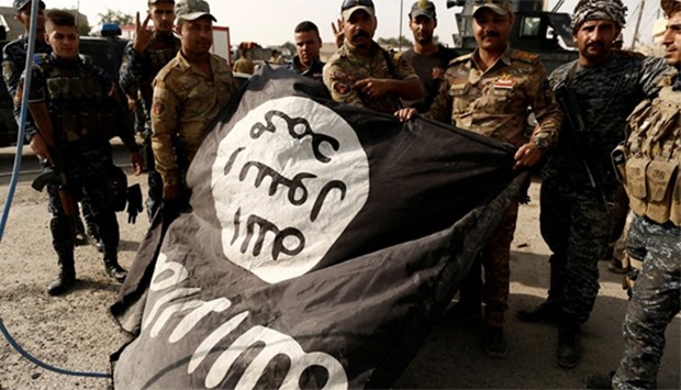 Iraqi soldiers pose with the Islamic State flag along a street of the town of al-Shura