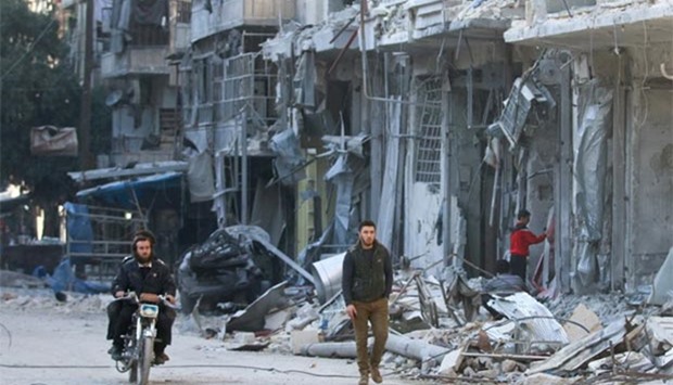 Men are pictured next to buildings damaged by airstrikes in the rebel-held al-Shaar neighbourhood of Aleppo on Thursday.