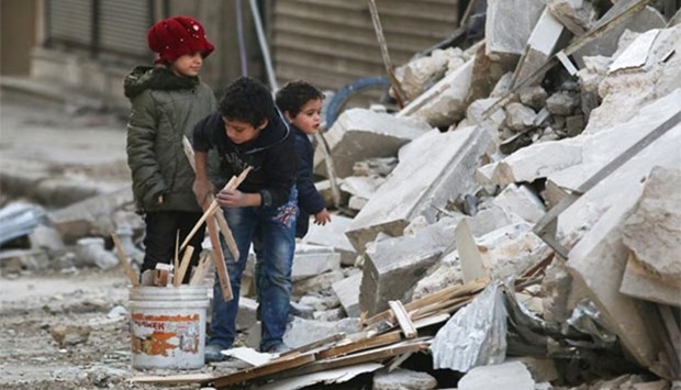 Children collect firewood amid damage and debris at a site hit by airstrikes in the rebel held al-Shaar neighbourhood of Aleppo on Thursday.