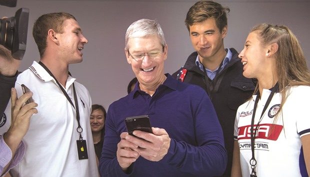 Apple CEO Tim Cook (centre) holds an iPhone 7 while speaking with attendees during an event in San Francisco. Cook is under pressure to deliver new products amid slowing sales of the iPhone, which accounts for two-thirds of Appleu2019s revenue.