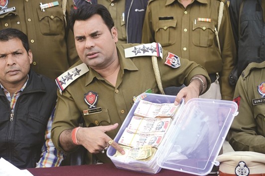 A police officer displays Rs500 and Rs1,000 notes recovered from a man identified as Rajiv Kumar during a press conference in Amritsar yesterday. Punjab police detained Kumar, resident of Faizabad in Uttar Pradesh and recovered Rs1.1mn of illegal currency.