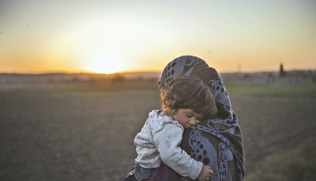 An Iraqi woman, who fled their village due to the fighting in Mosul, holds her child after crossing the Tigris River yesterday in the village of Tall Adh-Dhahab, some 10km south of Mosul. A group of civilians were forced out of Tall Adh-Dhahab and used as human shields by Islamic State group (IS) militants some weeks ago but managed to escape and to return to their home village.
