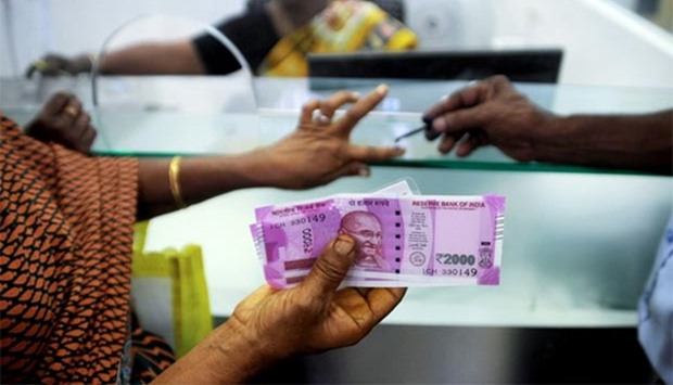 An Indian woman displays her 2000 rupees note as she has her finger inked with indelible ink after exchanging banknotes at a bank in Chennai.