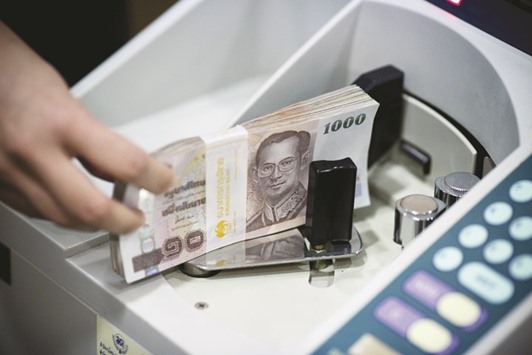 An employee places a bundle of Thai 1,000 baht banknotes in a money counting machine at the Krung Thai Bank headquarters branch in Bangkok. The baht has weakened 1.7% in November, the least after Taiwanu2019s dollar and Chinau2019s yuan among 11 Asian currencies tracked by Bloomberg.