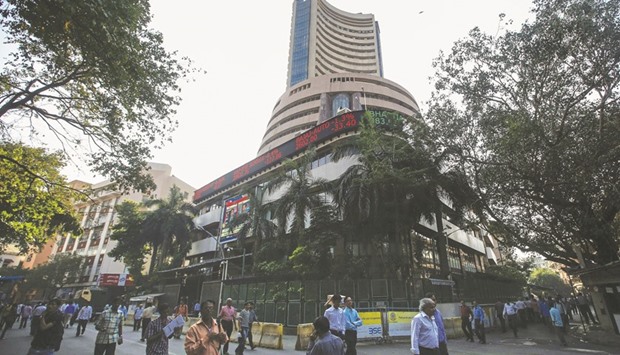 People walk by the Bombay Stock Exchange building in Mumbai. The BSE Sensex closed down 385 points to 25,765 yesterday.