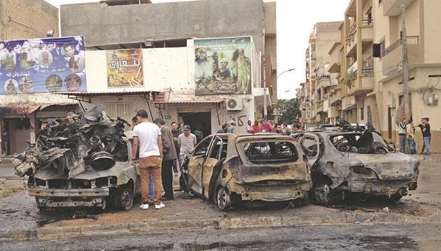 People look at the remnants of a car at the scene of a car bomb in Benghazi, Libya, yesterday.