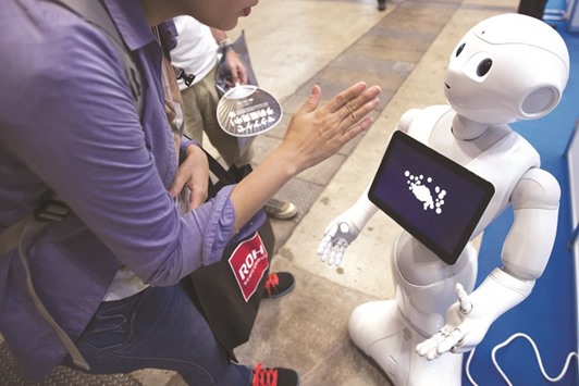 A visitor looks at a display screen on Softbank Groupu2019s Pepper humanoid robot at the Cutting-Edge IT & Electronics Comprehensive Exhibition (CEATEC) at Makuhari Messe in Chiba, Japan, on October 4. Abu Dhabi investor Mubadala Development Co would potentially join Saudi Arabia and Qatar in investing in SoftBanku2019s planned multi-billion dollar technology fund, people familiar with the matter have said.