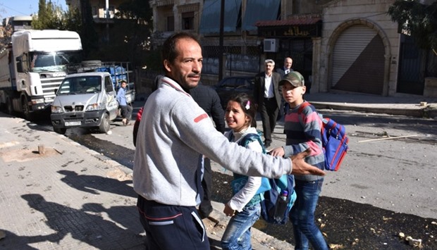A Syrian man evacuates children from a school reportedly hit by rebel rocket fire in the Furqan neighbourhood of the government-held side of west Aleppo, on November 20.