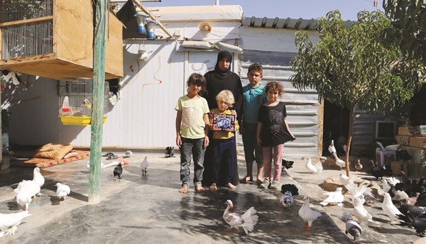 Nariman Qadhe, 30, the widow of a rebel fighter, poses for a photograph with her children as they hold a photograph of their late father in Zaatari camp in Jordan.