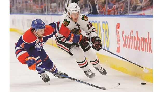 Edmonton Oilers Kris Russell (L) and Chicago Blackhawks Jonathan Toews battle along the boards for a loose puck.