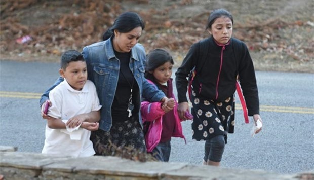 A woman escorts three children away from the scene of a school bus crash involving multiple fatalities in Chattanooga, Tennessee.