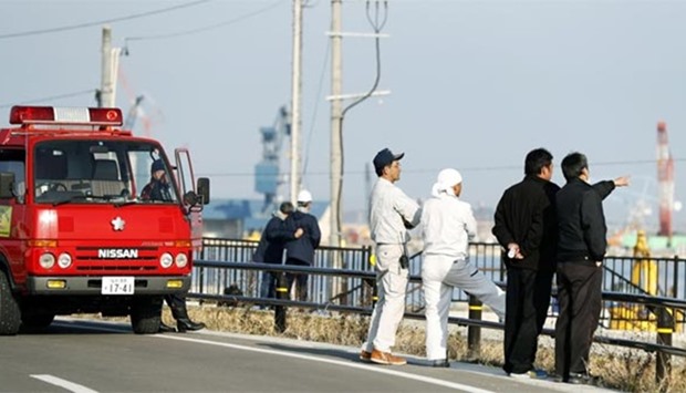 Firefighters and residents look towards the port to check the water level after tsunami advisories were issued following an earthquake in Soma, Fukushima prefecture, in this photo taken by Kyodo on Tuesday.