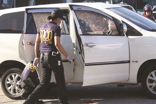 Investigators check the bullet-riddled vehicle of BIR director Jonas Amora, who was killed by unidentified assailants in Quezon City.