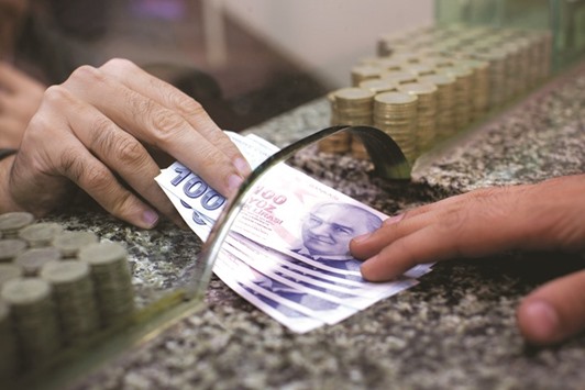 Turkish 100 lira bank notes are exchanged on a currency store counter in Istanbul (file). A plunging lira may force Turkeyu2019s central bank to raise interest rates for the first time in almost three years.