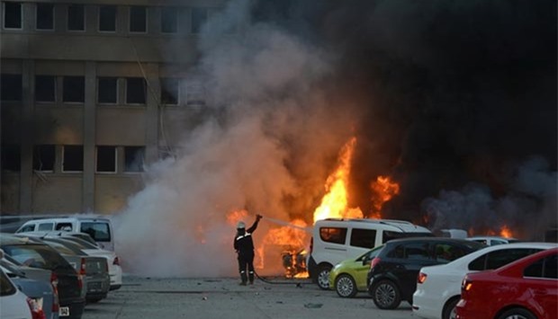A firefighter tries to extinguish burning vehicles after an explosion outside the governor's office in the southern Turkish city of Adana on Thursday.