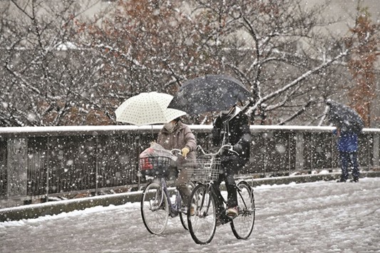 People cycle in a snowfall in Tokyo yesterday morning.