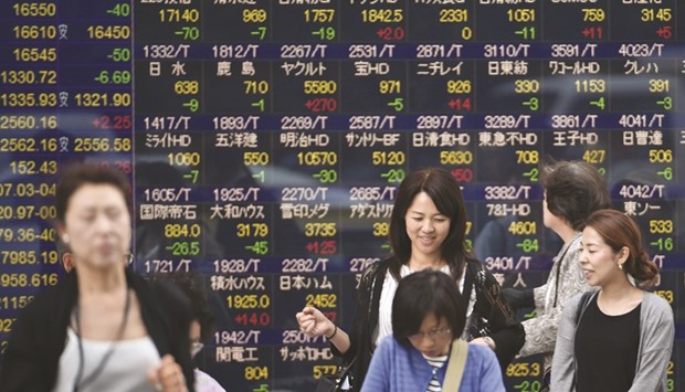 Pedestrians walk past an electronic quotation board in Tokyo. The Nikkei 225 closed up 0.3% to 18,381.22 points yesterday.