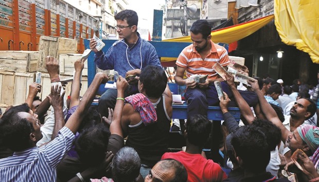 Vendors raise their Indian rupee banknotes at a wholesale fruits market in Kolkata. In a telephone conversation with IANS, Bank Employees Federation of India general secretary Pradip Biswas said the shortage of currency was not expected to subside for several months, even if all four presses in the country, which print currency notes, work at their maximum capacity.
