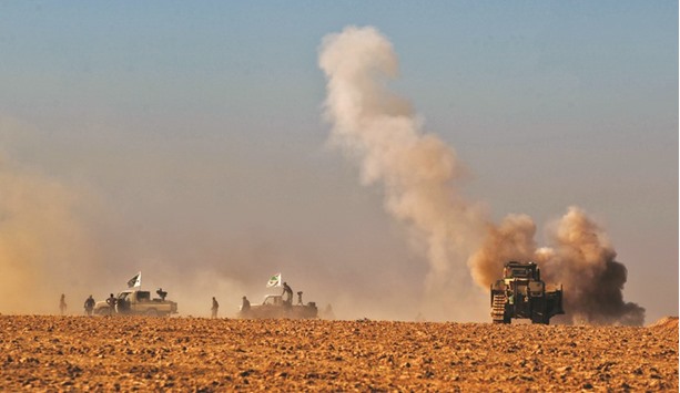 Smoke billows from a mine as fighters from the Popular Mobilisation hold a position near the village of al-Tofaha, southeast of the city of Tal Afar yesterday, during an ongoing operation against Islamic State (IS) group.
