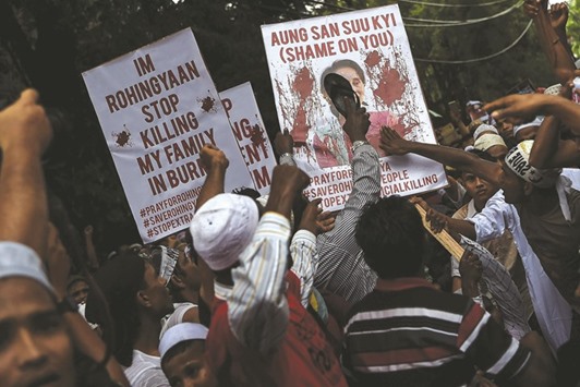 Ethnic Rohingya use a shoe to hit a placard with portrait of Suu Kyi during a protest yesterday outside the Myanmar embassy in Kuala Lumpur.