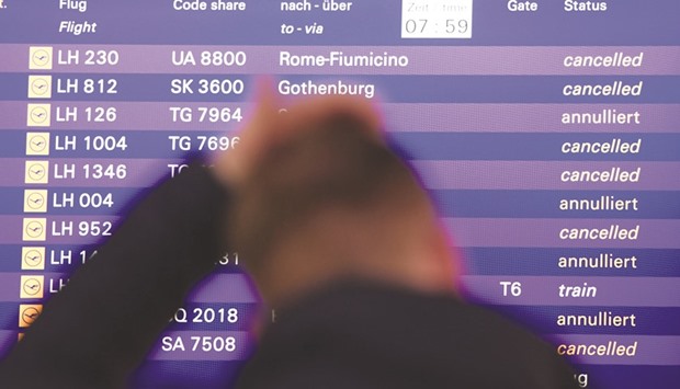 A flight passenger stands yesterday in front of a board displaying cancelled Lufthansa flights at the airport in Frankfurt am Main.