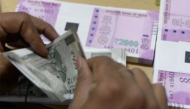 A bank staff member counts 500 rupees notes to give to customers in Mumbai.