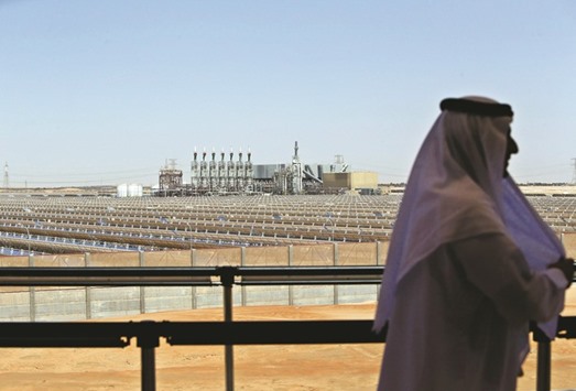 An Emarati man stands on a balcony overlooking the Shams 1, Concentrated Solar power (CSP) plant, in Al-Gharibiyah district on the outskirts of Abu Dhabi (file). The UAEu2019s latest solar power auction grabbed headlines in September when one group bid a record low 2.42 cents a kilowatt-hour to produce power.