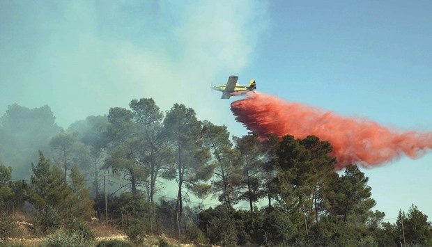 An Israeli firefighting plane helps extinguish a fire over the Halamish settlement, northwest of Ramallah near the village of Nabi Saleh in the occupied West Bank, as it helps extinguish an ongoing fire in the area, yesterday.