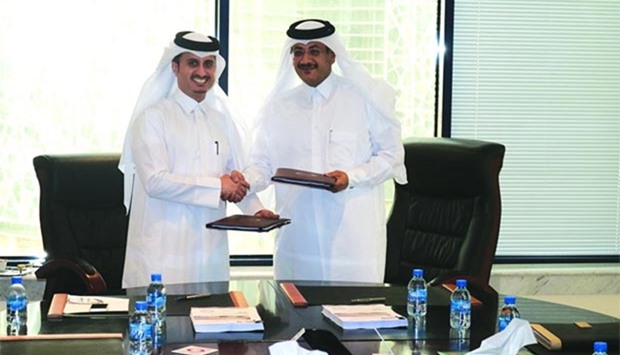 Q-Post's Faleh al-Naemi (right) and Malomatia's Yousef al-Naama exchange documents at the signing ceremony.