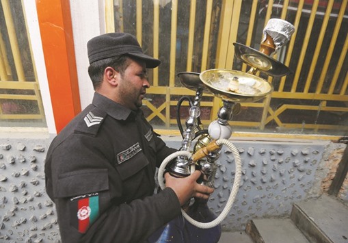 A policeman confiscates shisha water pipes from a shisha cafe during a raid in Kabul yesterday.