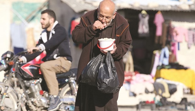 A man eats food that was distributed as aid in a rebel-held besieged area in Aleppo, Syria.