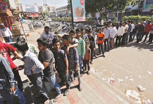 People queue outside an ATM of State Bank of India to withdraw cash in Ahmedabad yesterday.