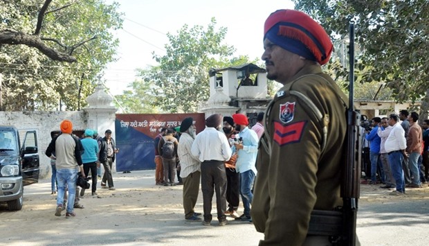 An Indian police personnel and onlookers stand near the gate of the Nabha maximum-security jail in Nabha