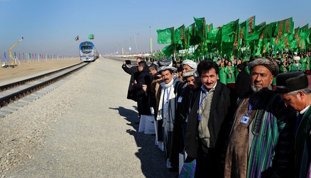 Officials and Turkmen traditional dancers gather at Turkmenistan's Imamnazar customs point on November 28, 2016 as they watch a freight train heading to Afghanistan's Akina during a ceremony marking the opening of the first section of a $2 billion railway link between the two countries.