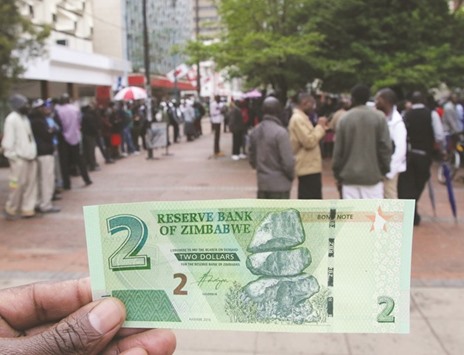 A woman holds up the new bond note outside a bank in Harare.