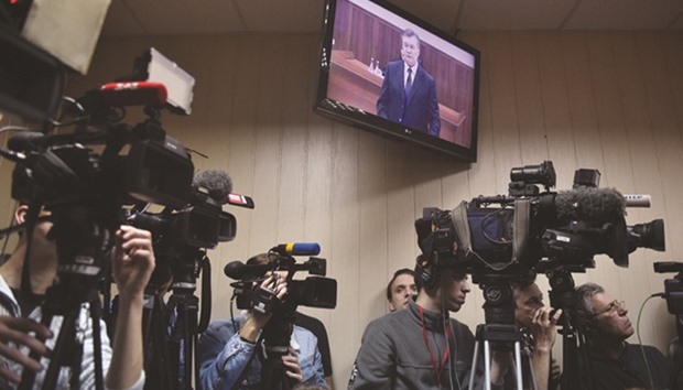 Journalists are at work at a Kiev courtroom as Yanukovych is seen via live video link from Russia.
