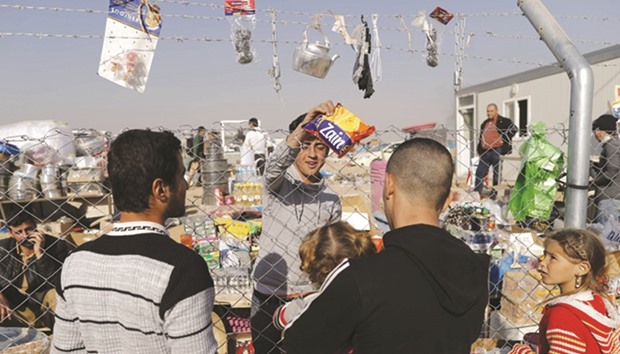 Internally displaced Iraqis buy items from local vendors from behind the fence at the Al Khazer refugee camp near Mosul.