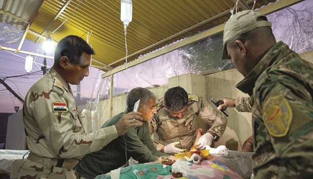 Captain Osama Fuad Rauf works on a patient as others hold cell phones above for additional light at the Iraqi Armyu2019s 9th Armored Division medical clinic.