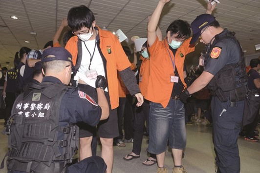 This picture released by Taiwanu2019s Criminal Investigation Bureau shows policemen checking Taiwanese fraud suspects as they arrive the Taoyuan International airport.