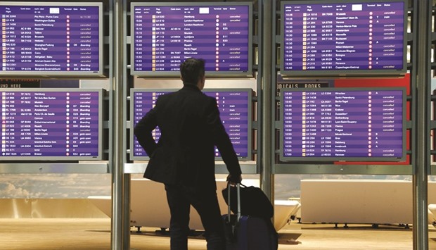 A flight passenger stands before an information board that shows most Lufthansa flights as cancelled yesterday.