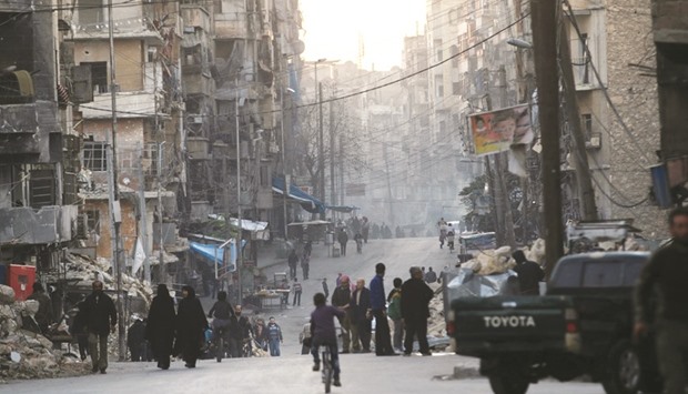 People walk along a street near damaged buildings in Tariq al-Bab neighbourhood of Aleppo, Syria yesterday.