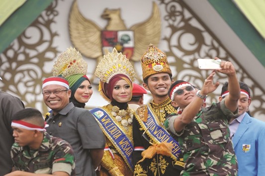 Indonesians military personnel and officials gather for a photograph with performers  during an u201cArchipelago Unityu201d gathering, being held across the country to call for peace and reduce tensions ahead of a protest tomorrow, in Banda Aceh yesterday.
