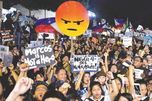 Anti-Marcos protesters chant slogans and hold up signs as they call for the exhumation of the body of the late dictator Ferdinand Marcos from the Heroesu2019 Cemetery following his burial, during a protest rally at the People Power Monument in Quezon city.