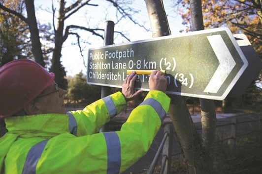 Tony Bennett, secretary of the organisation Active Resistance to Metrication (ARM) prepares to cover up part of a sign displaying the metric system in Brentwood, southeast England on November 28, 2016. Armed with high-vis jackets, a ladder and a half-inch spanner, Tony Bennett and Derek Norman are the footsoldiers of Brexit, waging a slow but successful battle against metrication, one street at a time.