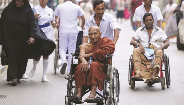A hospital worker wheels in a Buddhist monk patient at an empty government hospital in Colombo yesterday. State doctors stopped their work to protest government plans to tax private incomes of medical practitioners as they staged a one-day strike.